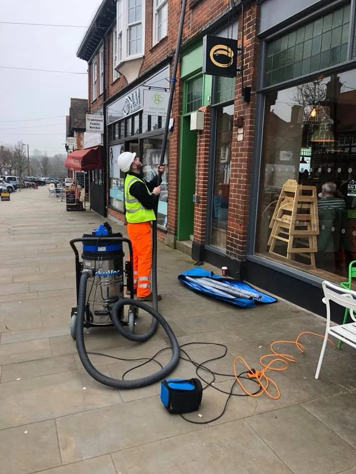 a man in an orange vest is cleaning a sidewalk